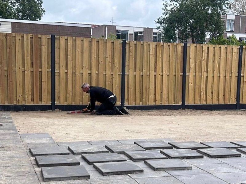 Vakman legt tegels voor een nieuwe houten schutting