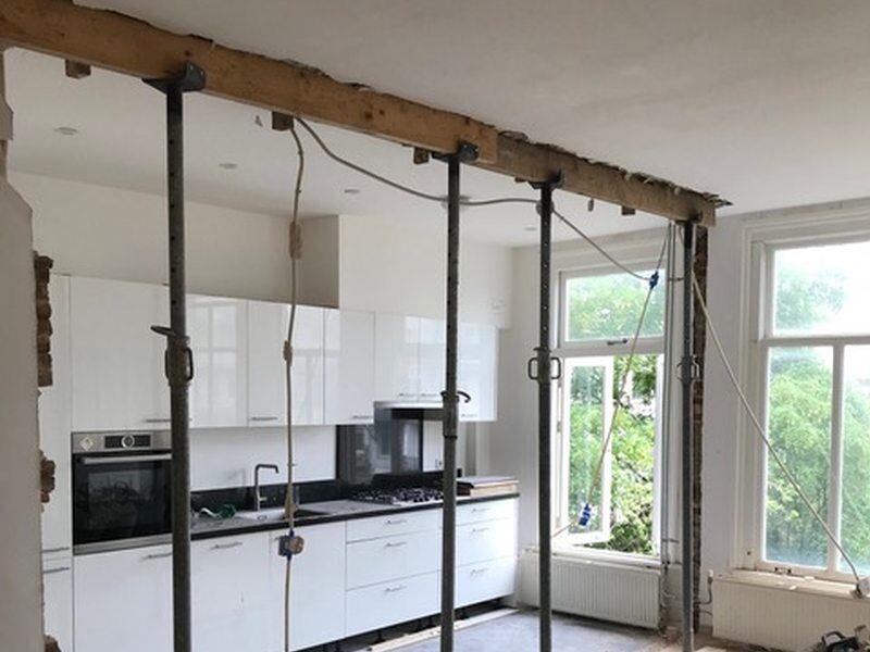 Tijdelijke stempels onder een balk in een woning met keuken